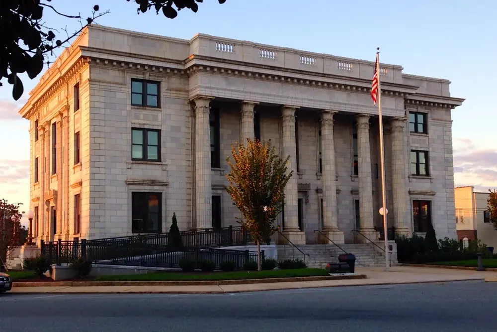 Columned marble Alamance County Courthouse with a flagpole at sunset in Graham, North Carolina