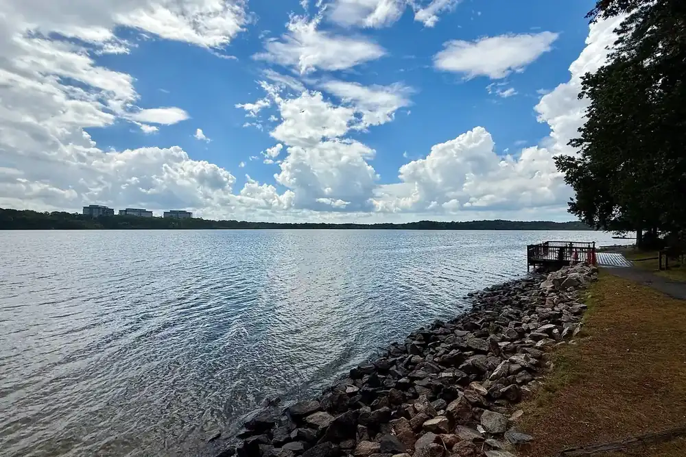 Rocky shoreline and open water of Lake Crabtree under summer clouds near Morrisville, North Carolina